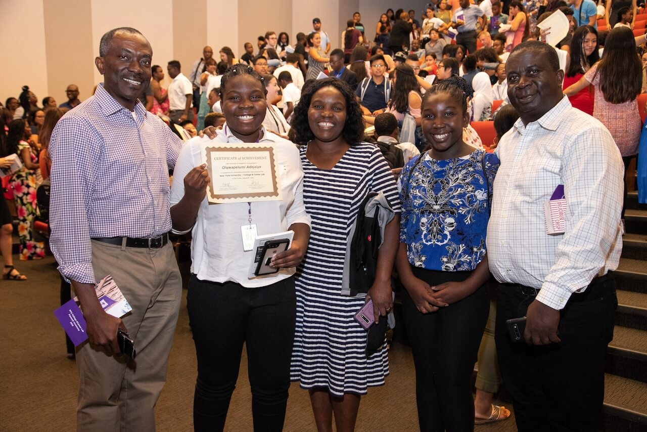 CCL student displaying a certificate, in an auditorium, surrounded by faculty